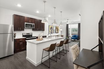 A modern kitchen with a white island and brown chairs.